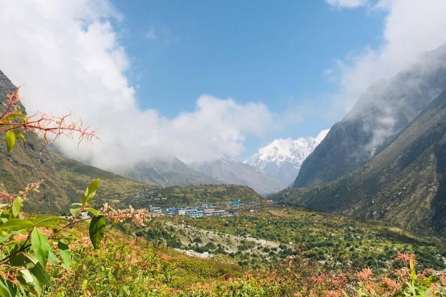 Langtang village with snow-capped mountain peak visible through clouds and mist